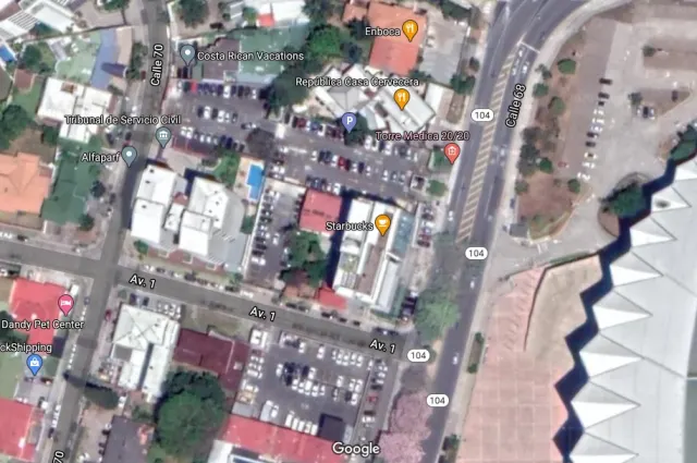 Vista satelital de cuadras urbanas que muestra calles, edificios y estacionamientos con etiquetas de texto superpuestas.