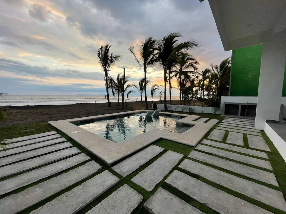 Piscina y palmeras en una casa de playa de Tivives mientras cae el sol sobre el Pac&iacute;fico